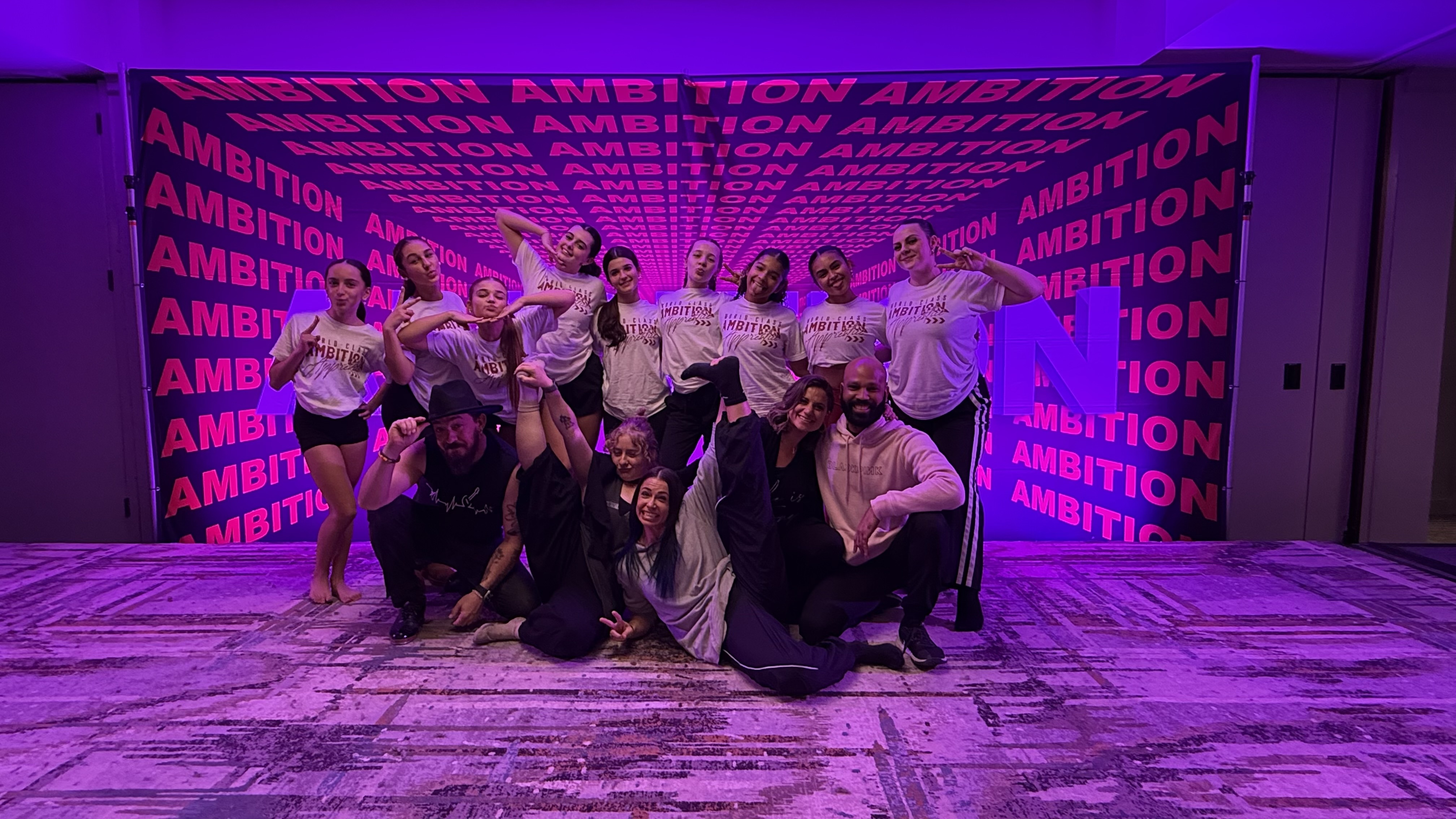 Ambition faculty and dancers in front of the workshop backdrop